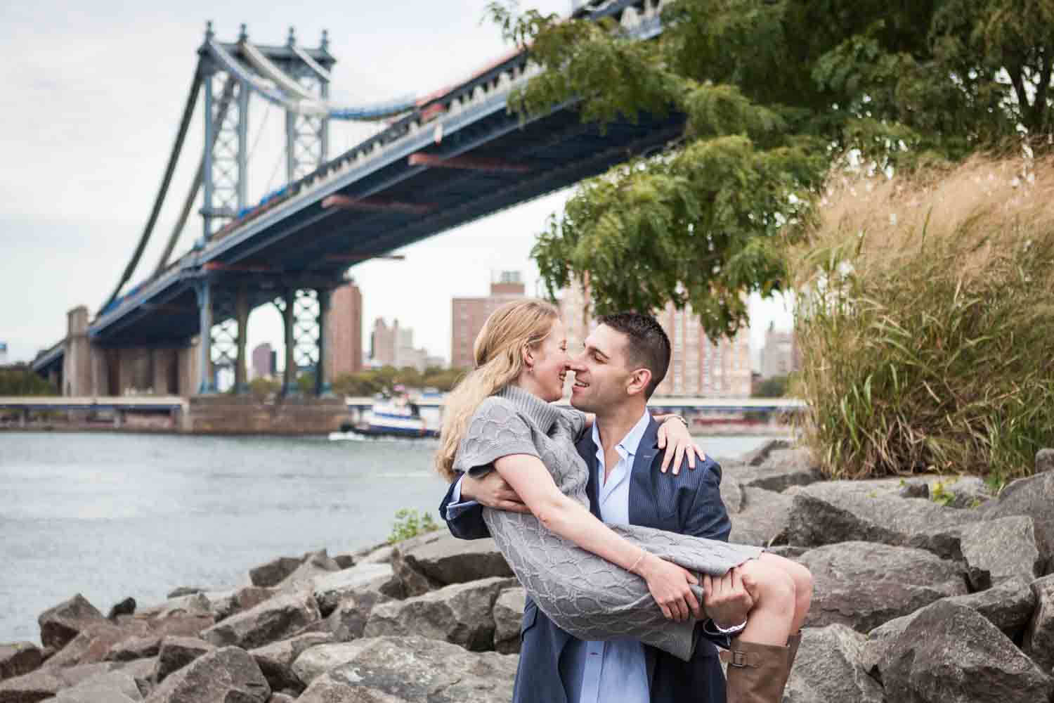 Man holding woman with Manhattan Bridge in background