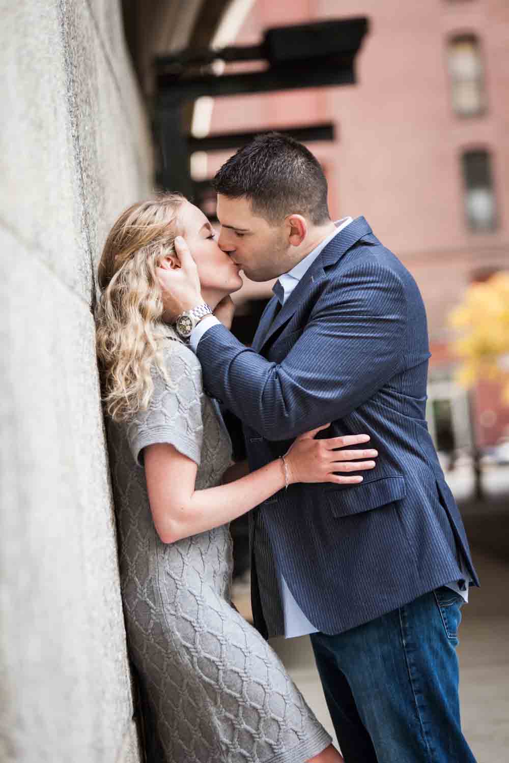 Woman kissing man wall during a Brooklyn Bridge Park engagement shoot