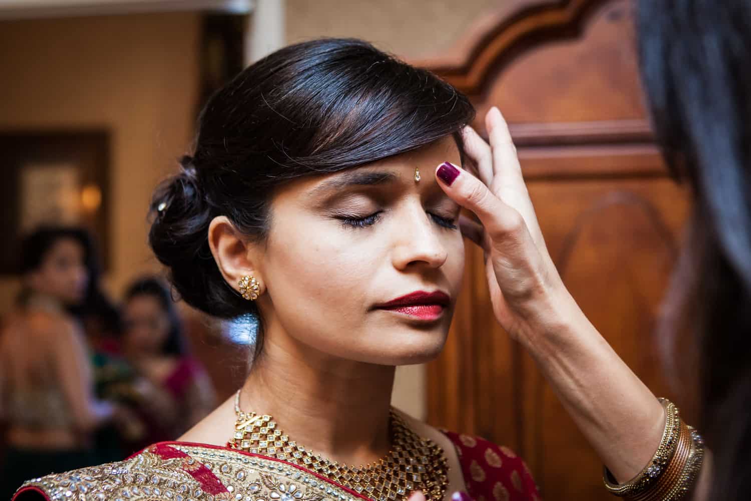 Hand applying bindi to bride