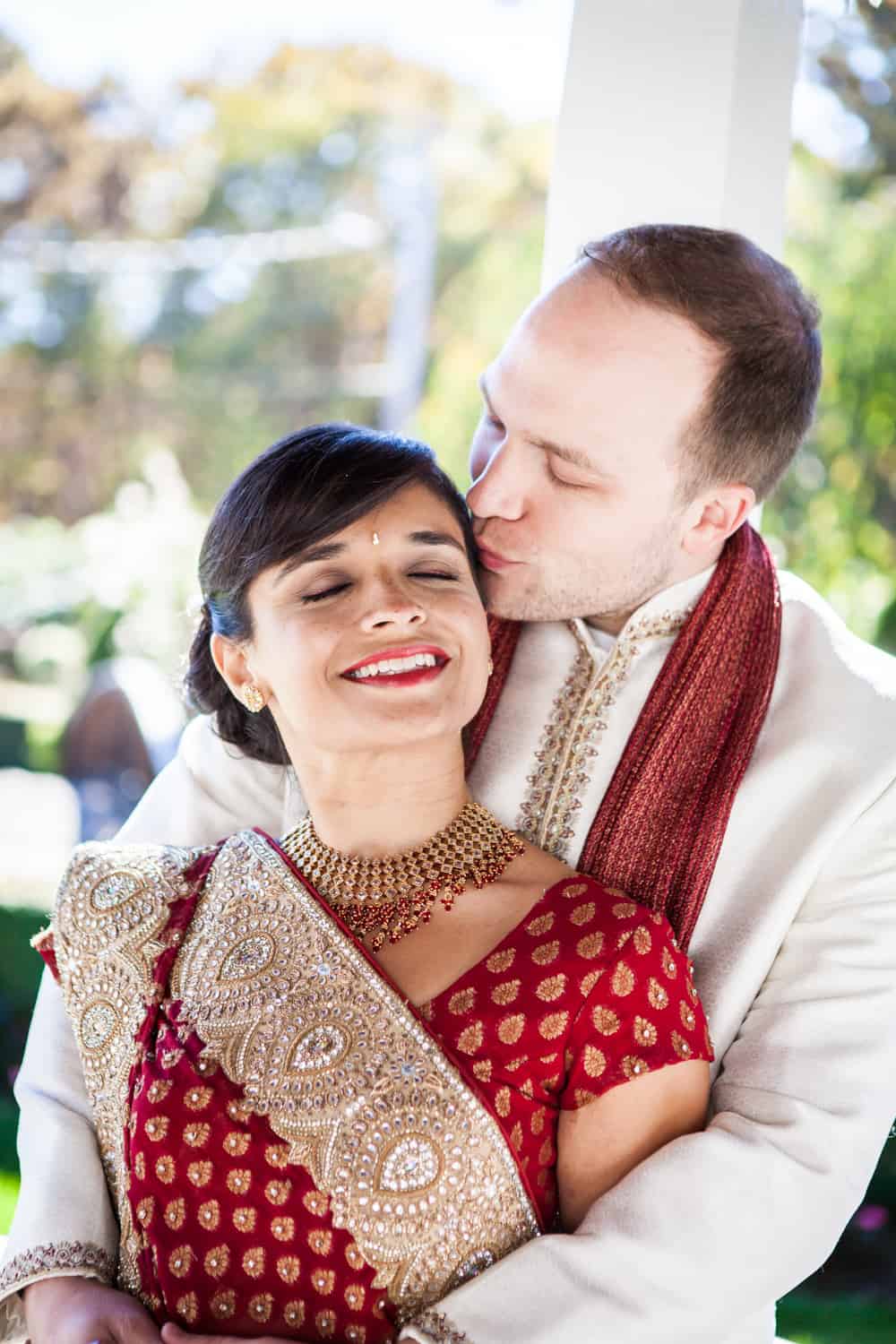 Groom kissing bride while wearing traditional Indian attire Bride and groom wearing traditional wedding attire at an East Wind Inn wedding