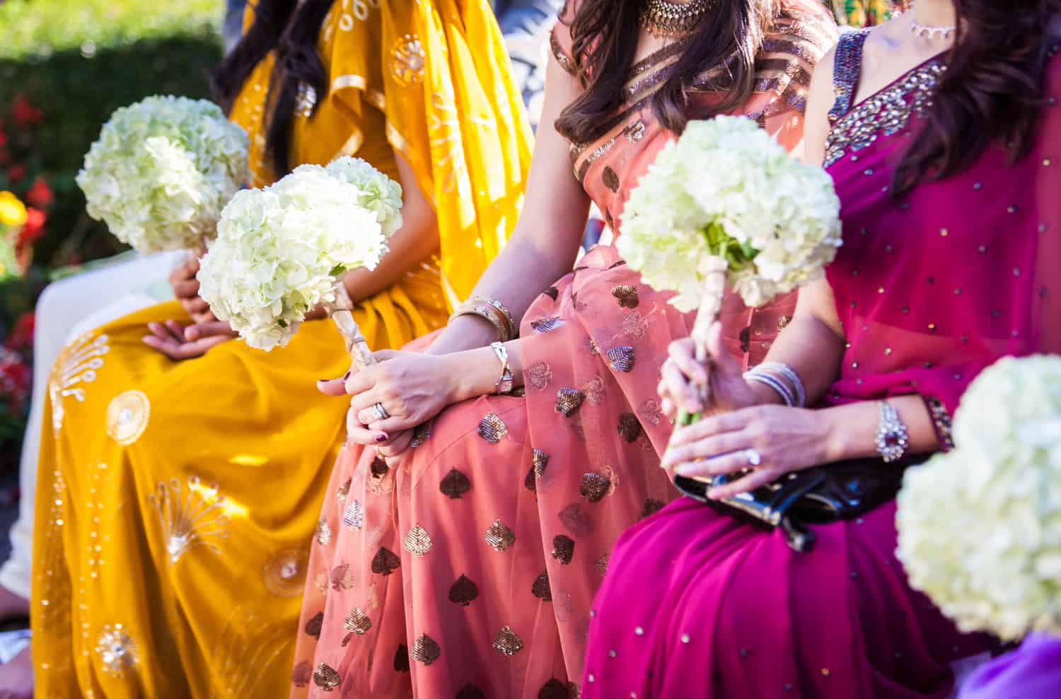 Close up on bridesmaids wearing colorful saris and holding bouquets