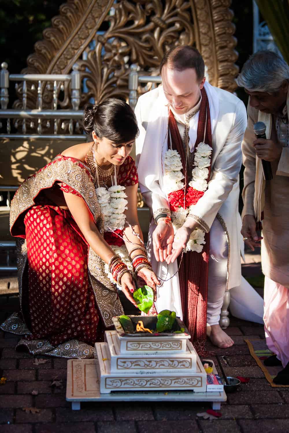 Bride and groom putting leaves in fire during traditional Hindu wedding ceremony