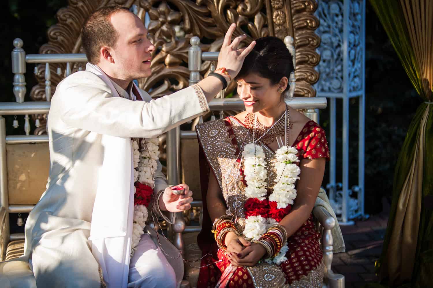 Groom putting bindhi on bride during traditional Hindu wedding ceremony