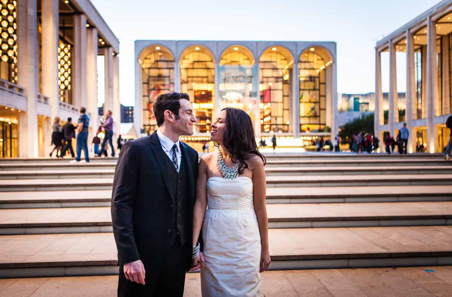Bride and groom holding hands in front of Lincoln Center