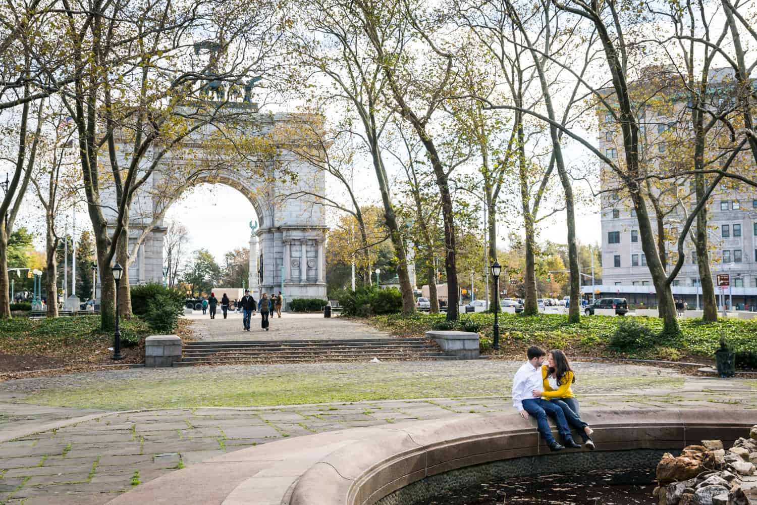 Grand Army Plaza engagement photos of couple sitting on side of fountain