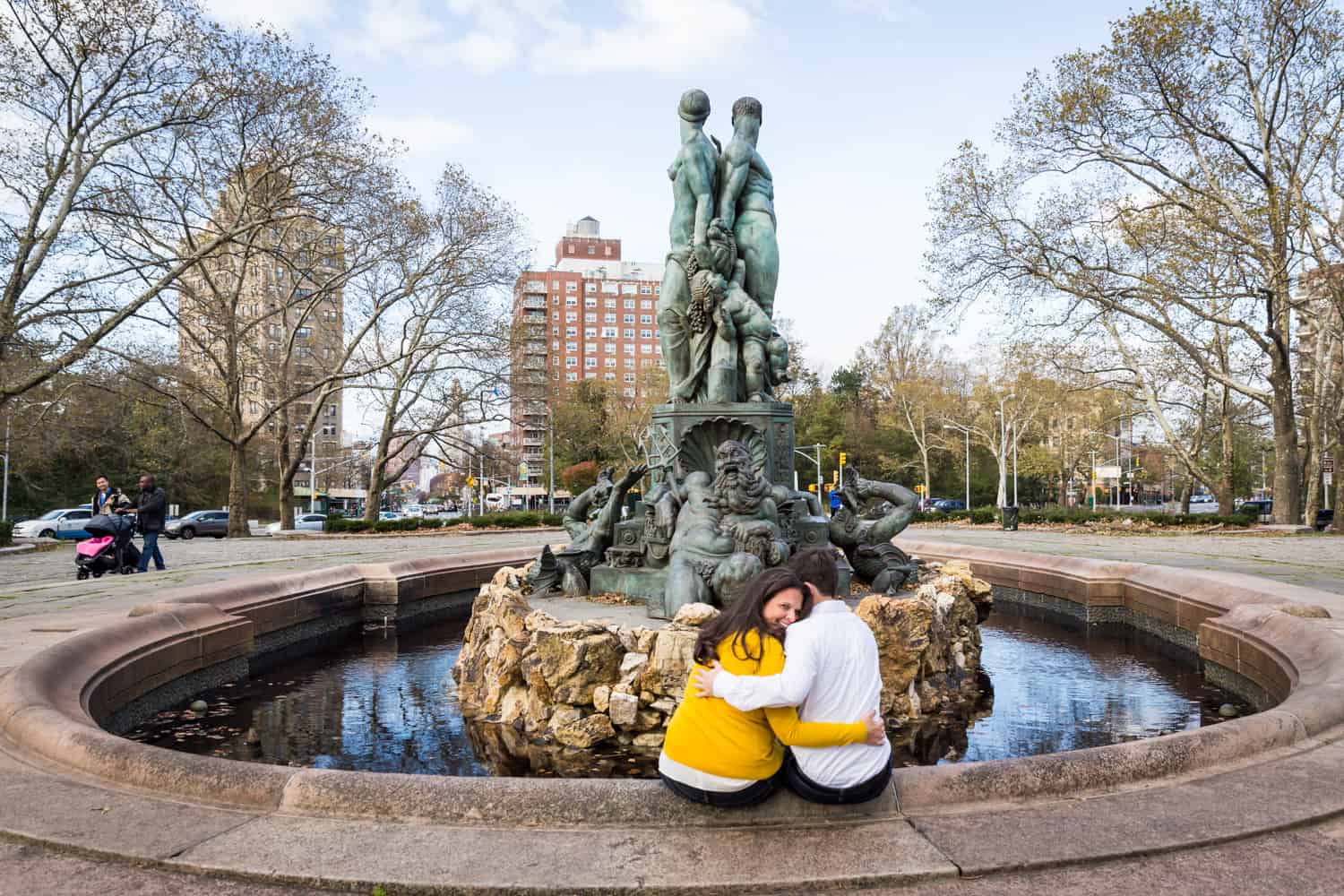 Grand Army Plaza engagement photos of couple sitting on side of fountain