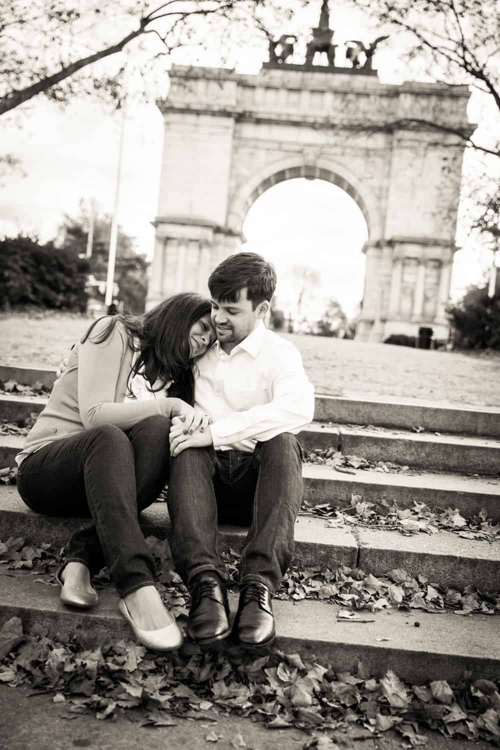 Black and white photo of couple cuddling on Grand Army Plaza steps