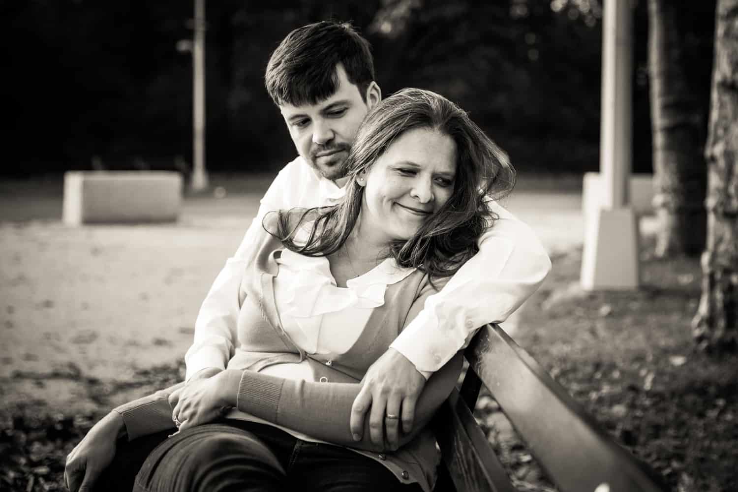 Black and white photo of couple cuddling on bench in Grand Army Plaza