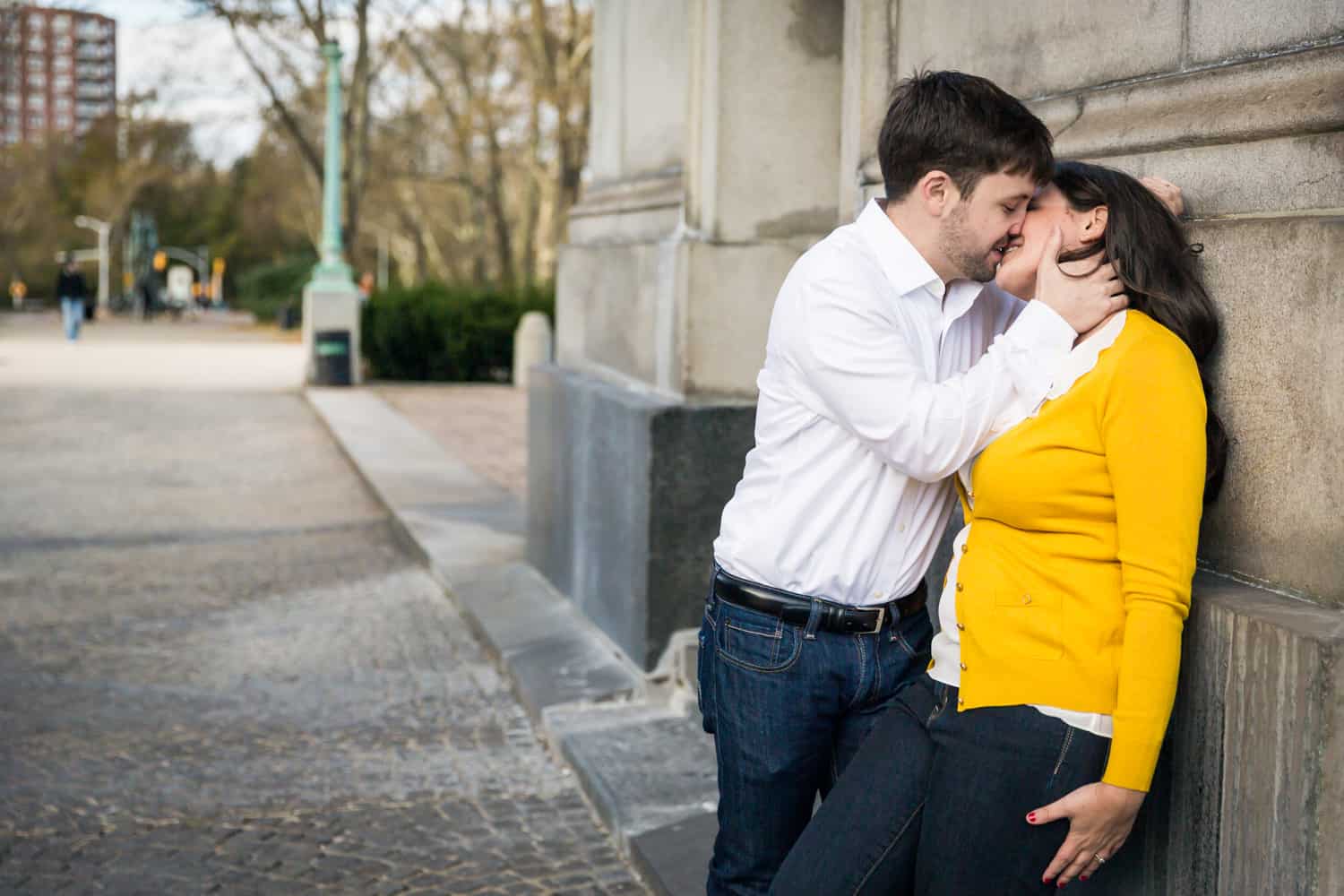 Grand Army Plaza engagement photos of couple kissing up against arch