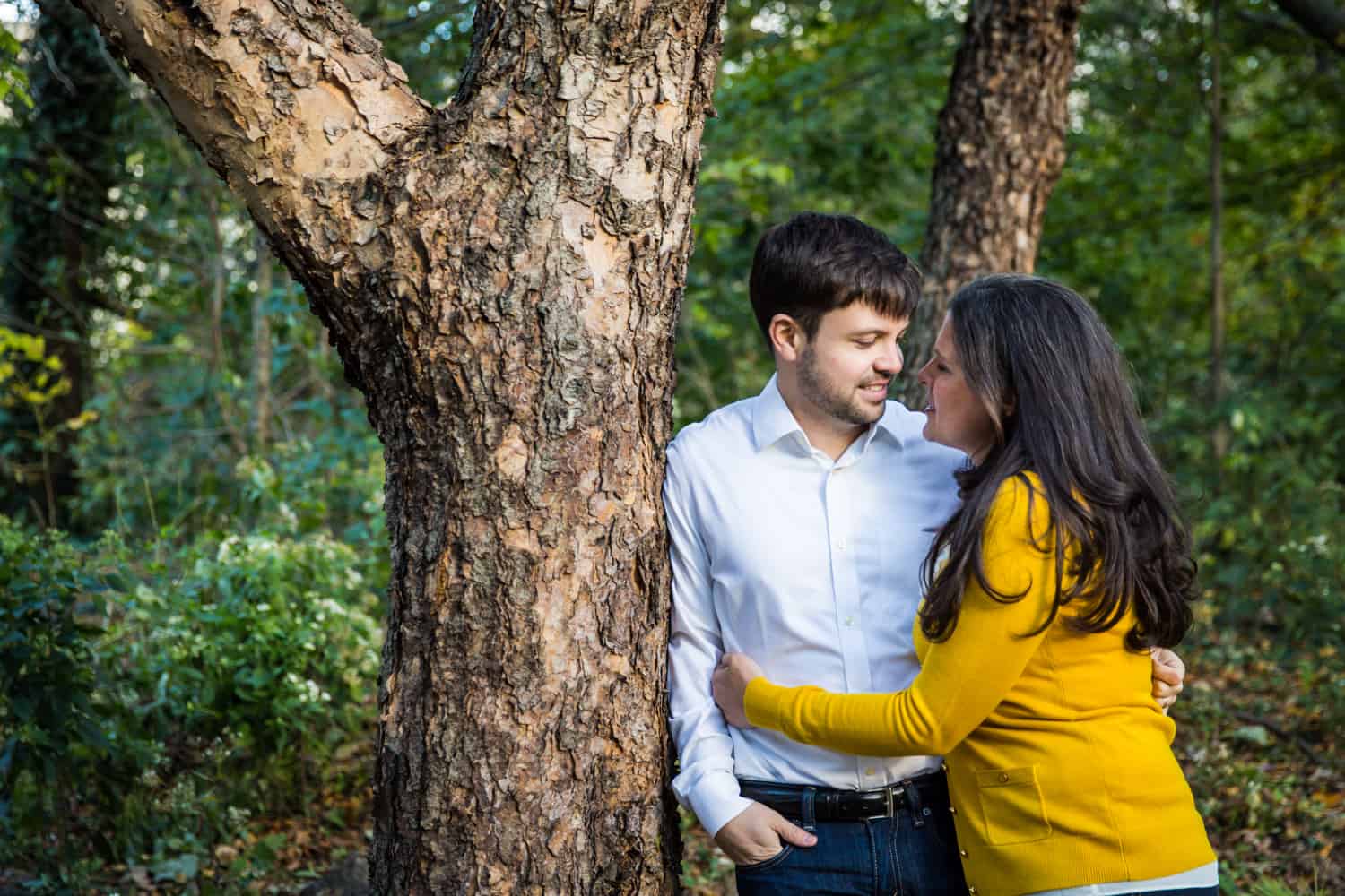 Couple hugging against tree in Prospect Park