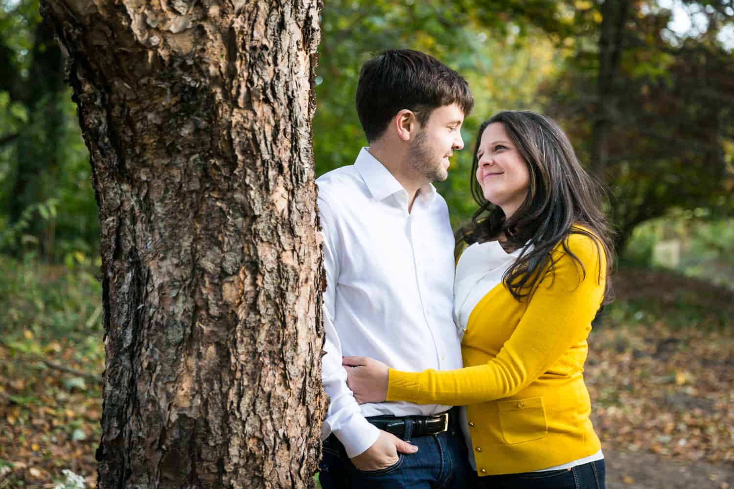 Couple cuddling next to tree in Prospect Park