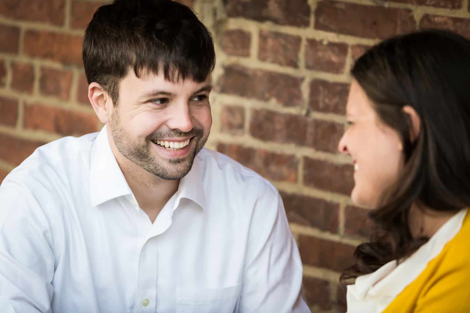 Couple laughing in front of brick wall