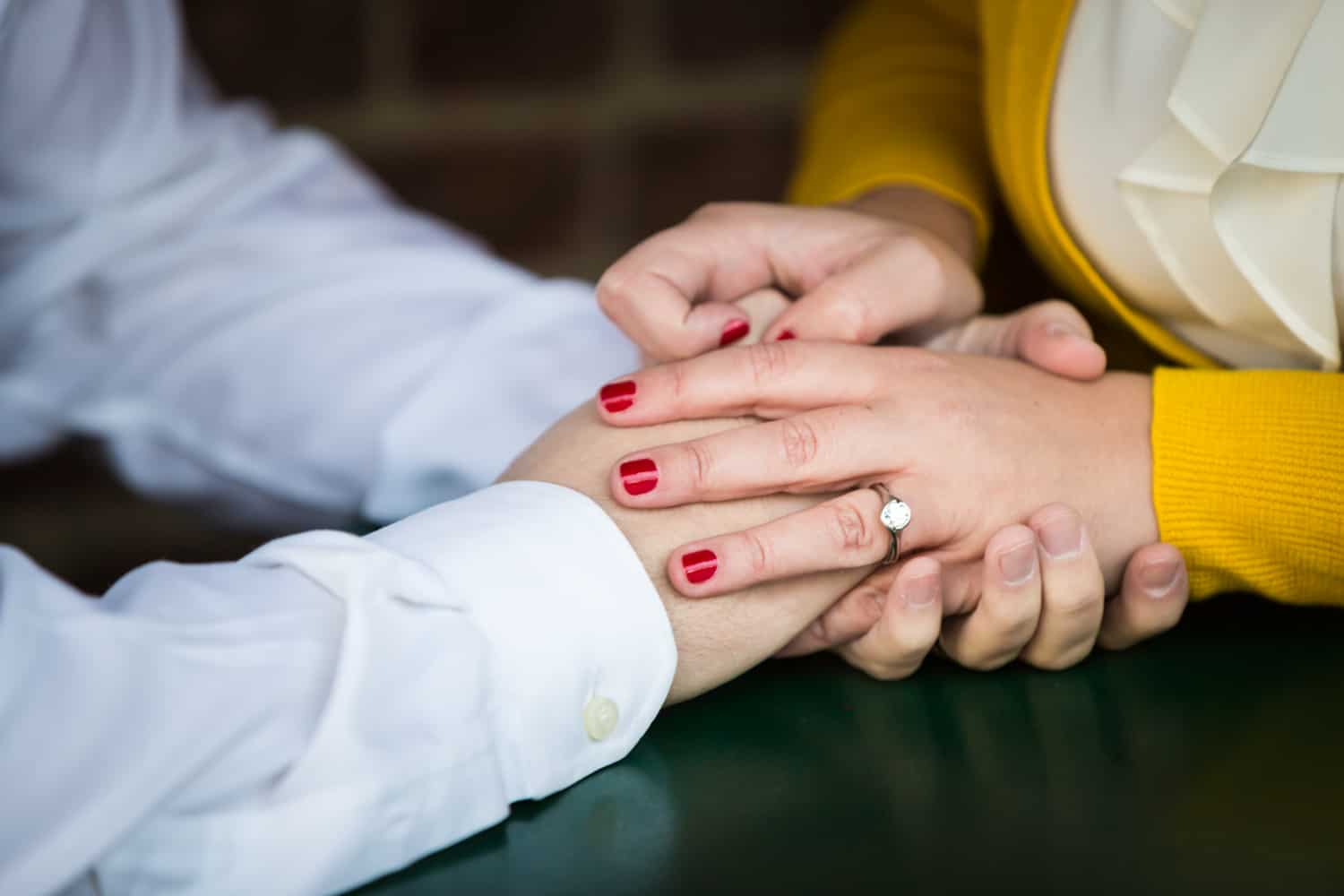 Close up of couple's hands with woman wearing engagement ring