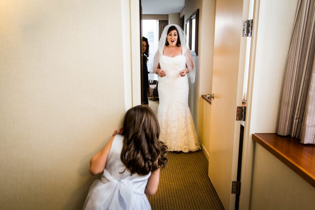 Little girl seeing bride walk down hallway