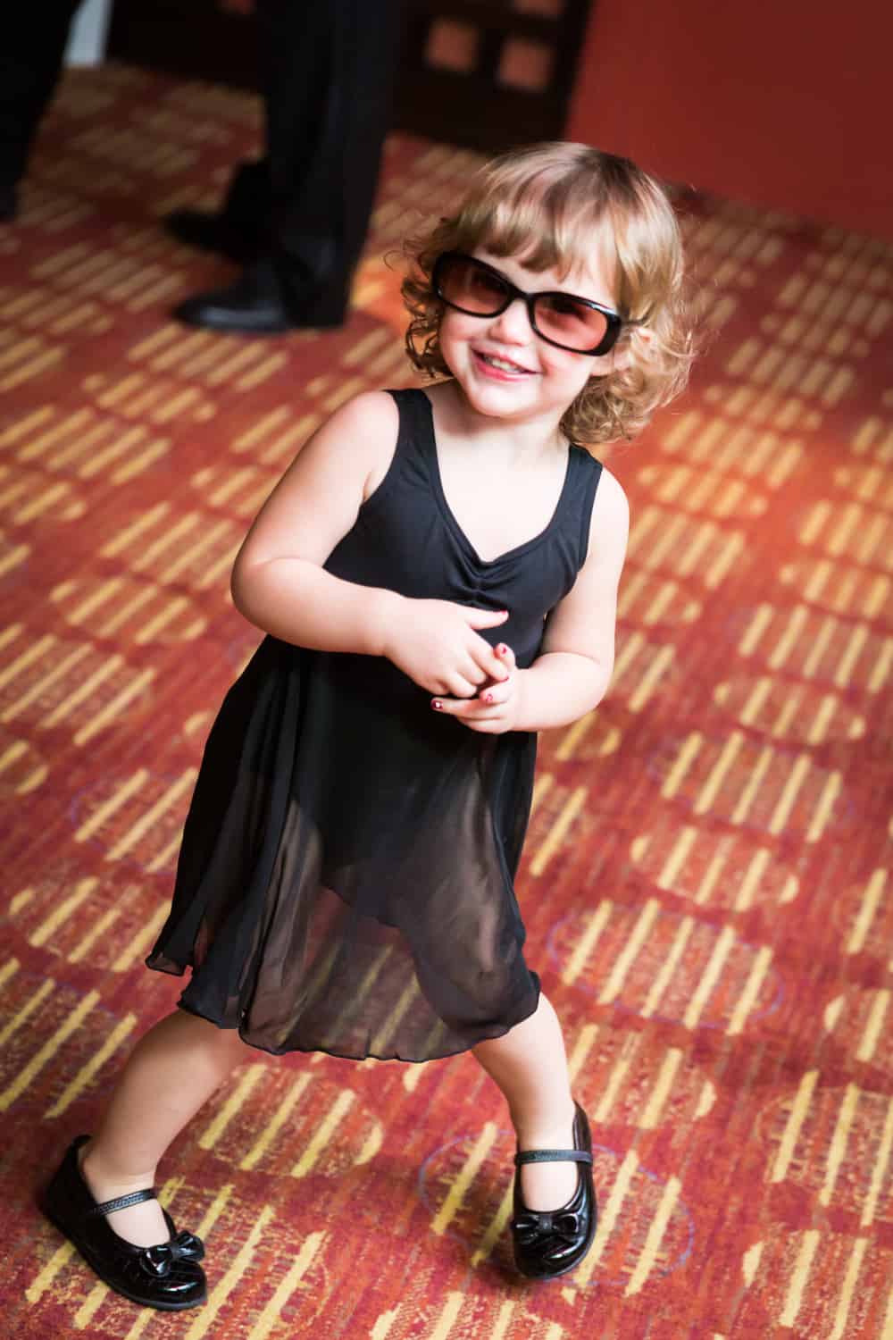 Little girl in black dress and sunglasses dancing