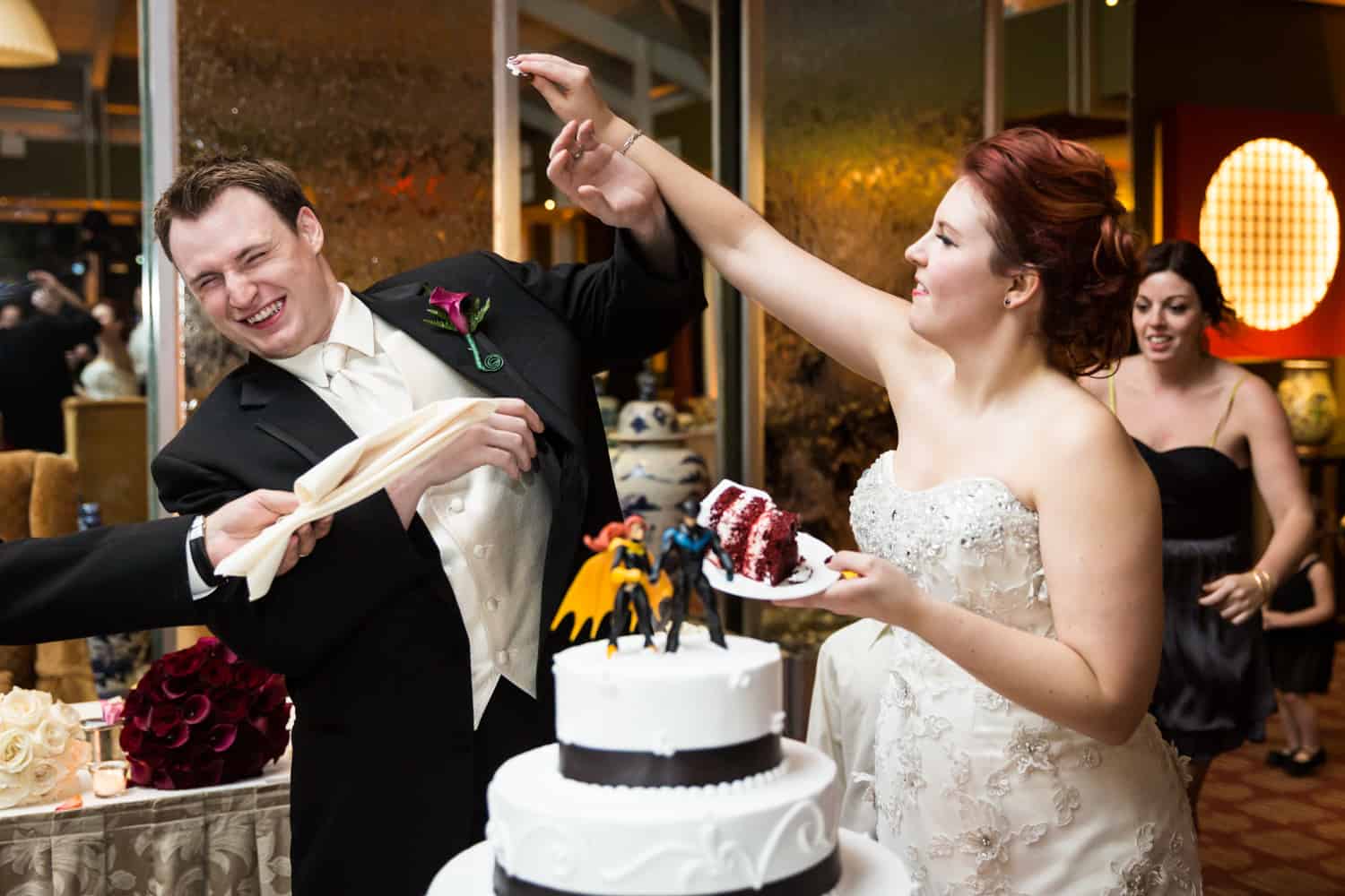 Nicotra's Ballroom wedding photos of bride trying to put cake on groom