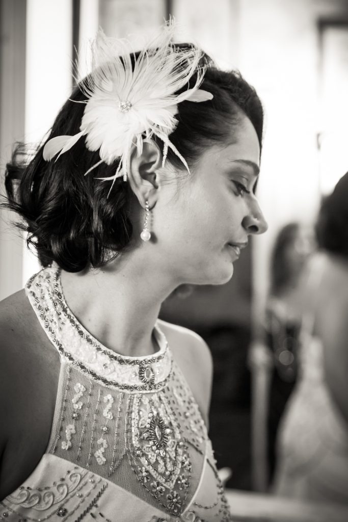 Black and white photo of bride with feathered barrette and beaded 1920s-style dress