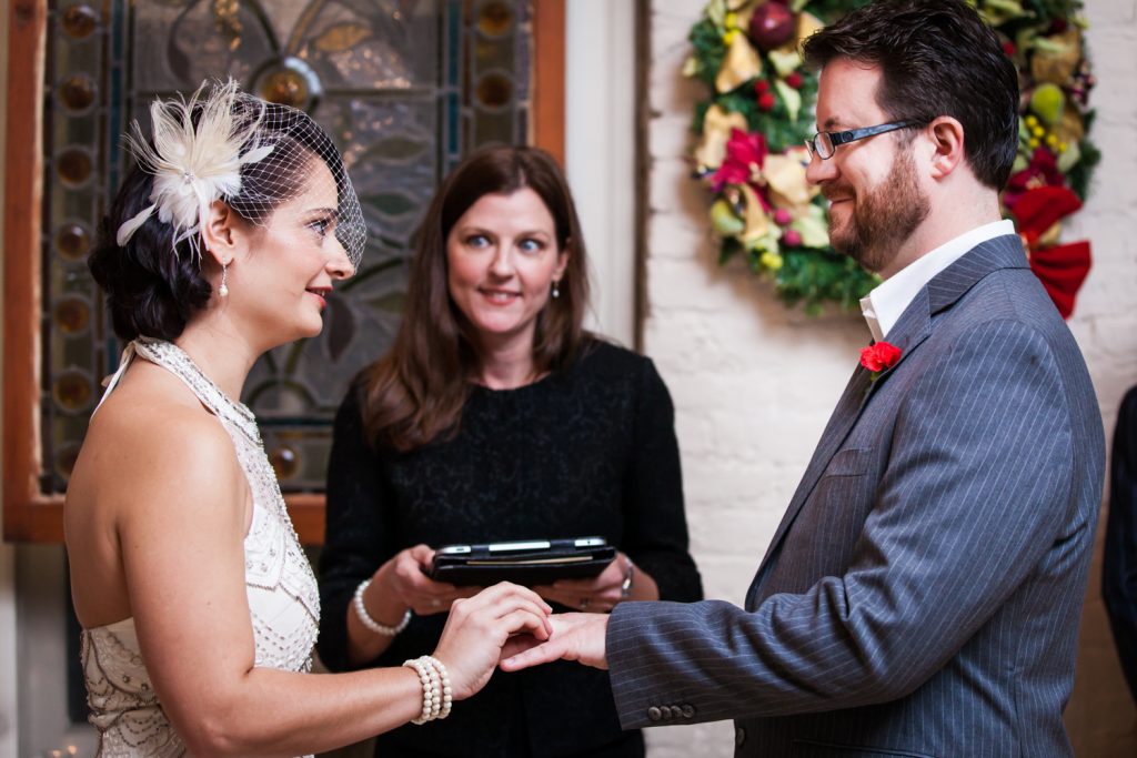 Alger House wedding photos of bride putting ring on groom's finger during ceremony