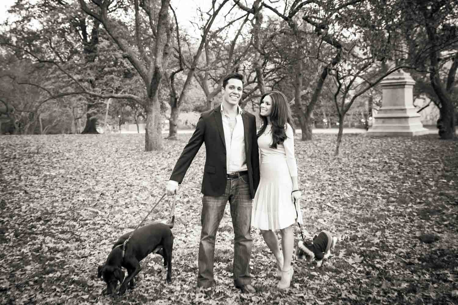 Black and white photo of couple walking with two dogs in Central Park