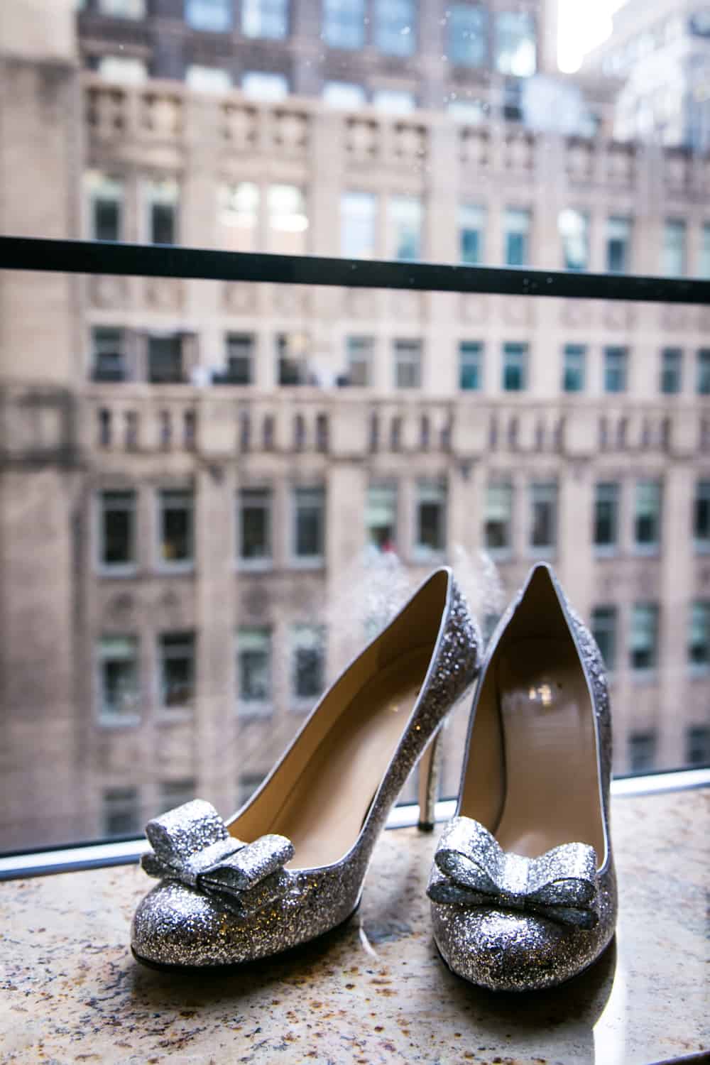 Silver glitter high heels with bows on windowsill