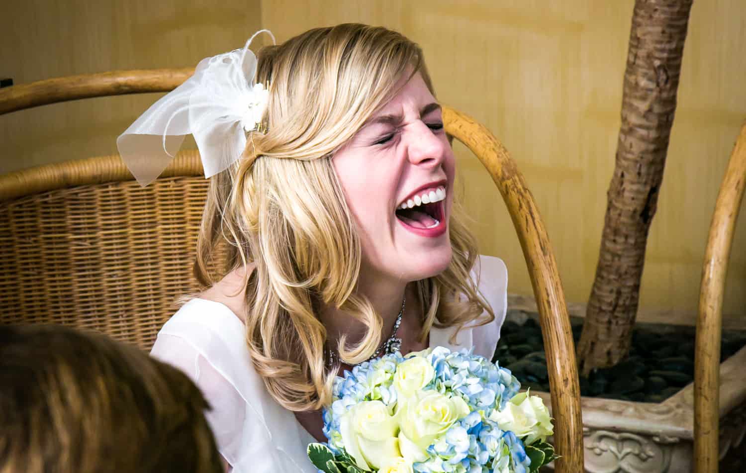 Bride laughing with eyes closed and holding bouquet
