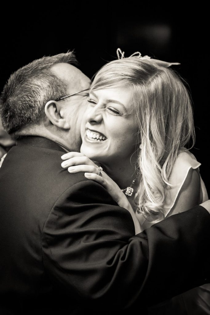 Black and white photo of bride hugging guest