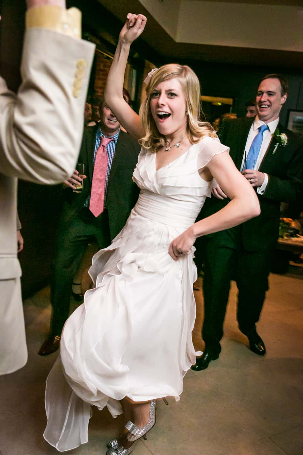 Bride holding up skirt and dancing with arm in air