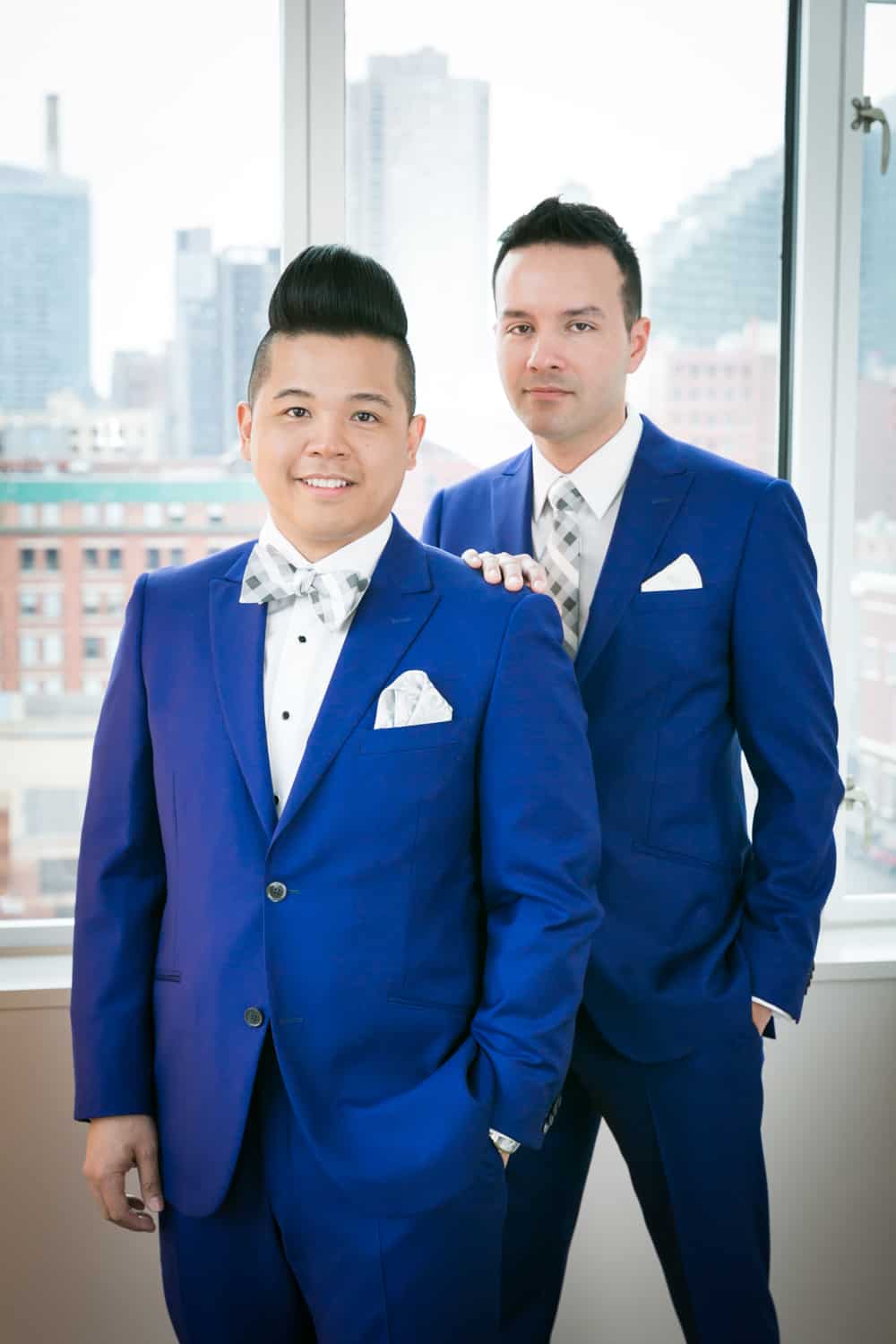 Two grooms in front of window