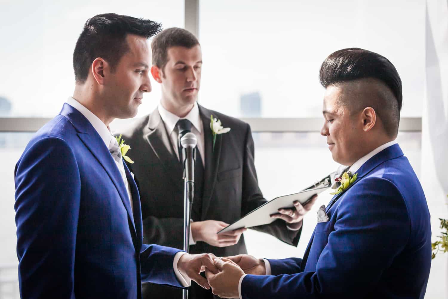 Two grooms exchanging rings at a Lighthouse at Chelsea Piers wedding