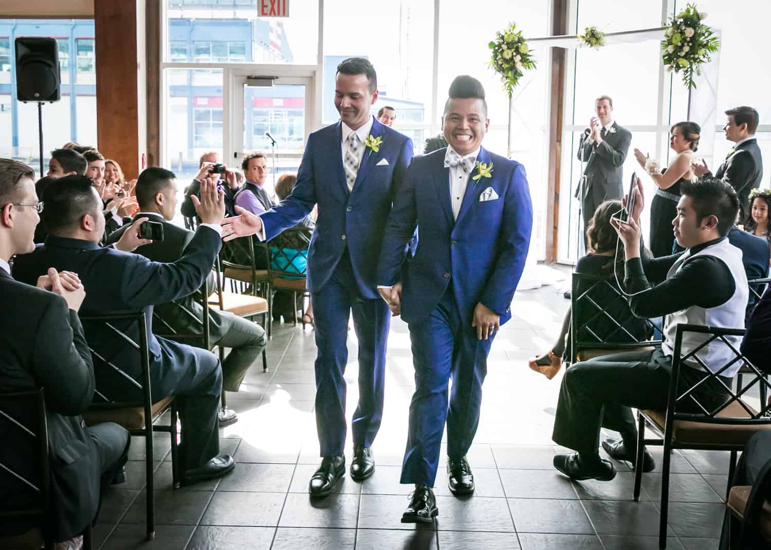 Two grooms walking out of ceremony at a Lighthouse at Chelsea Piers wedding