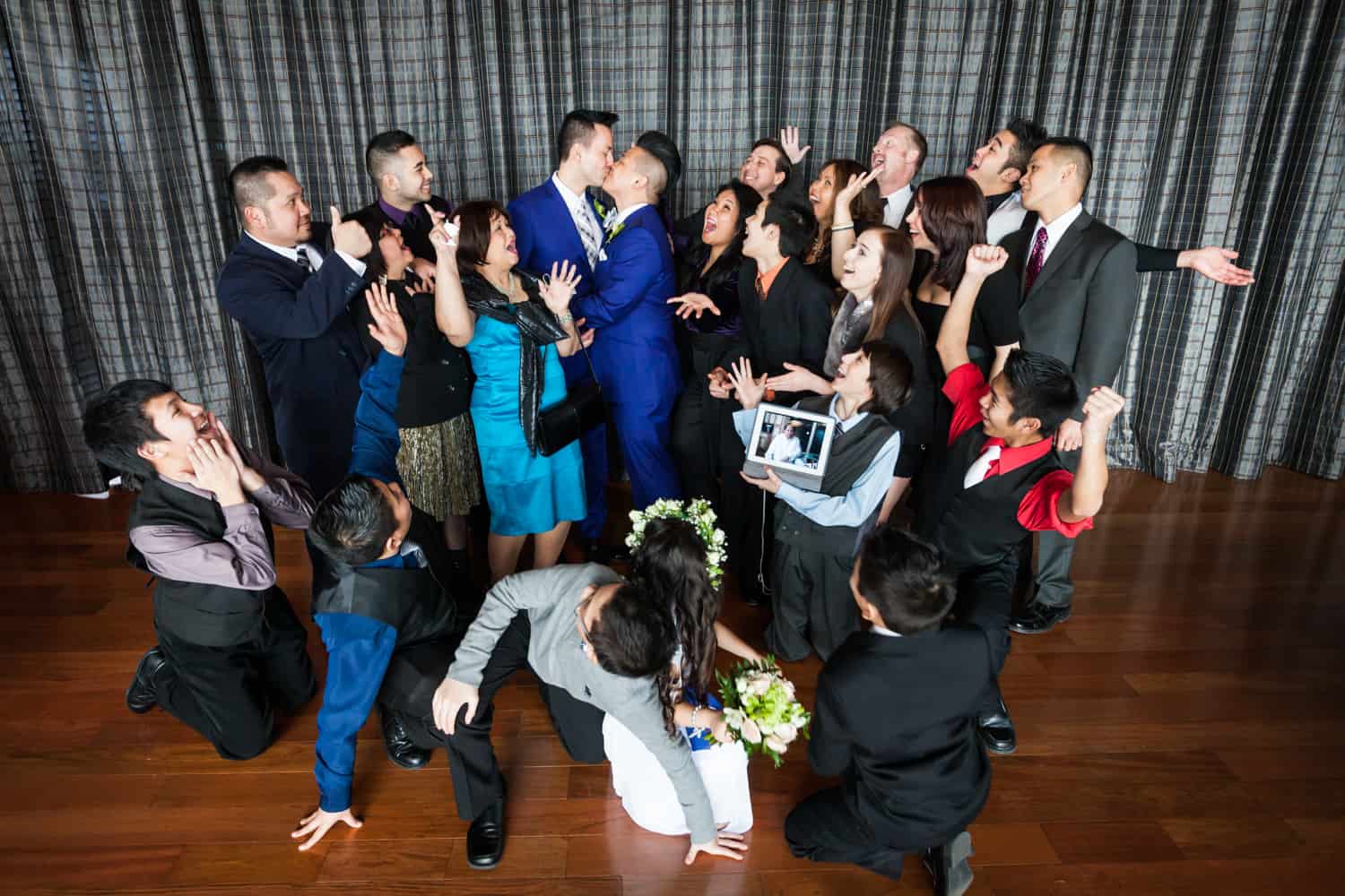 Family cheering around two grooms kissing