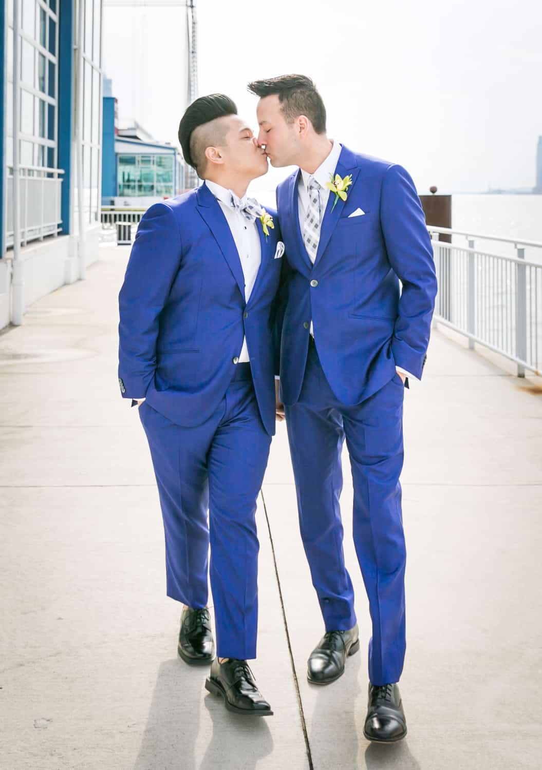 Two grooms kissing and walking beside Hudson River waterfront