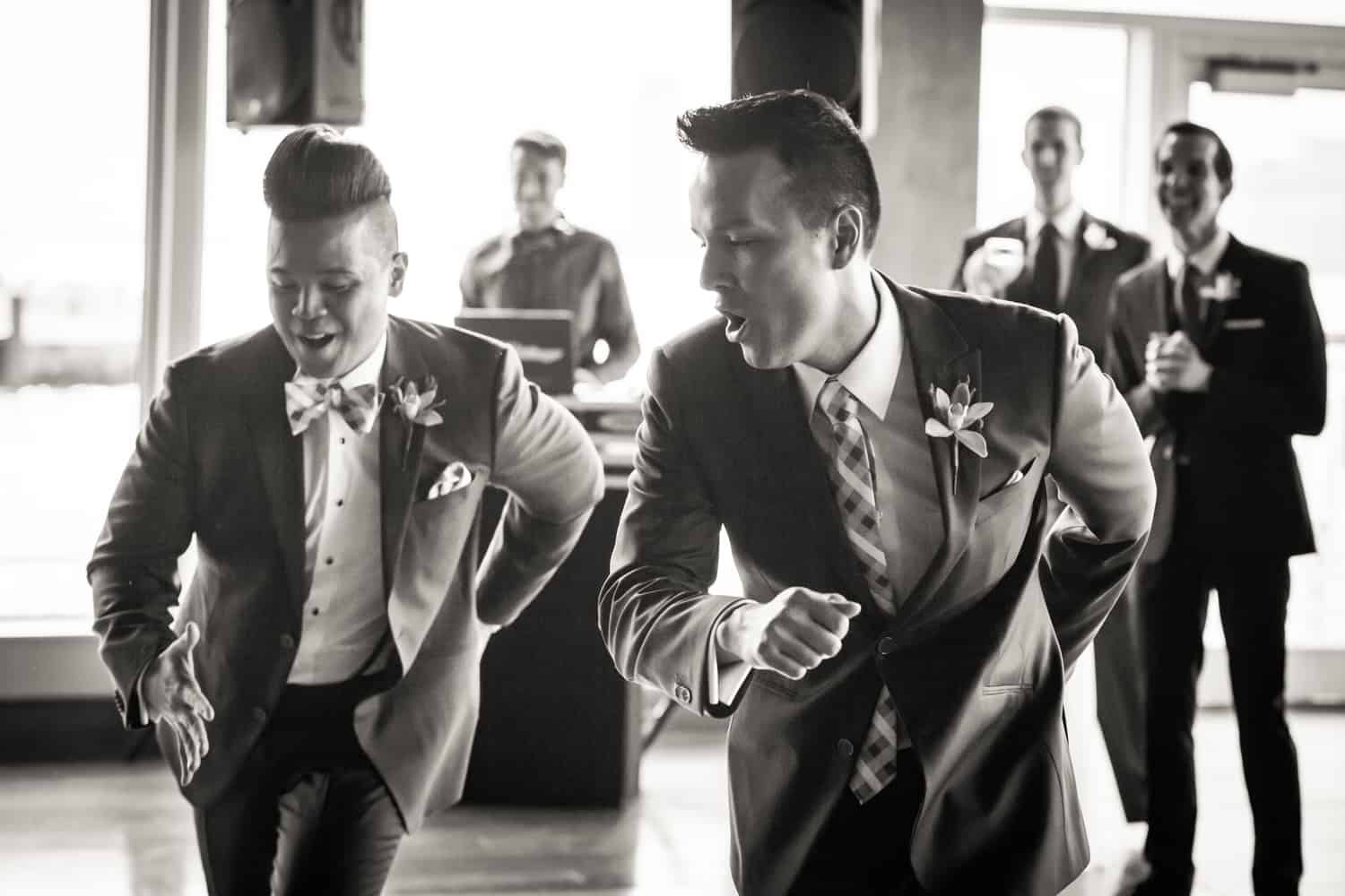 Black and white photo of two grooms dancing in front of guests at a Lighthouse at Chelsea Piers wedding