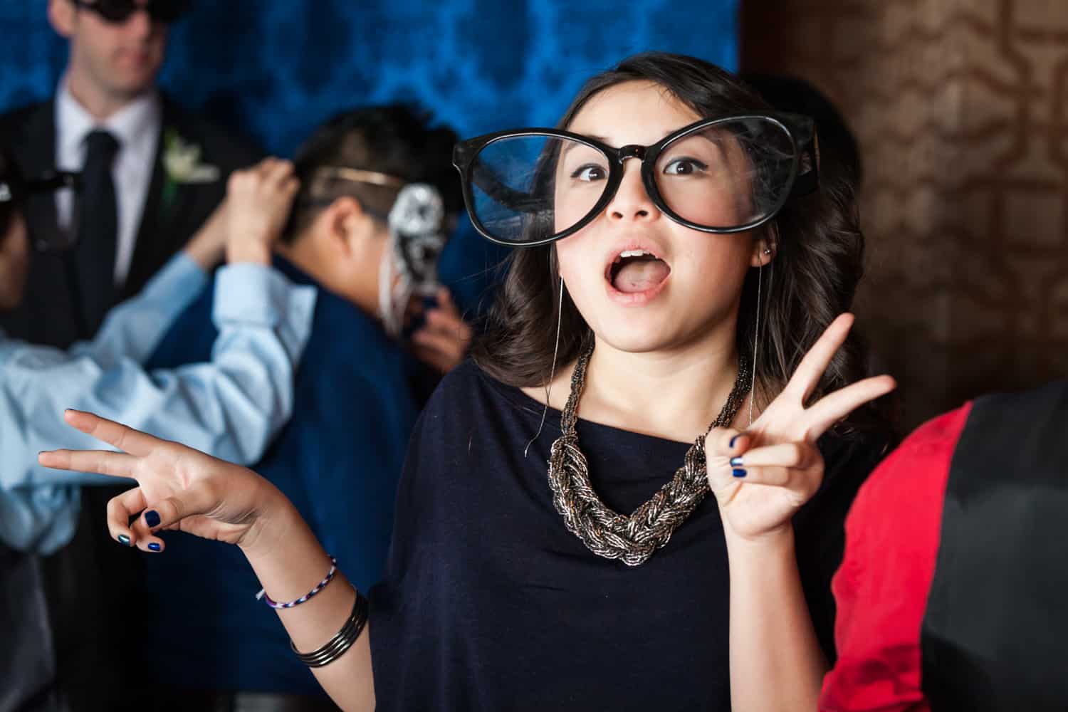 Young girl wearing oversized glasses at photobooth at a Lighthouse at Chelsea Piers wedding