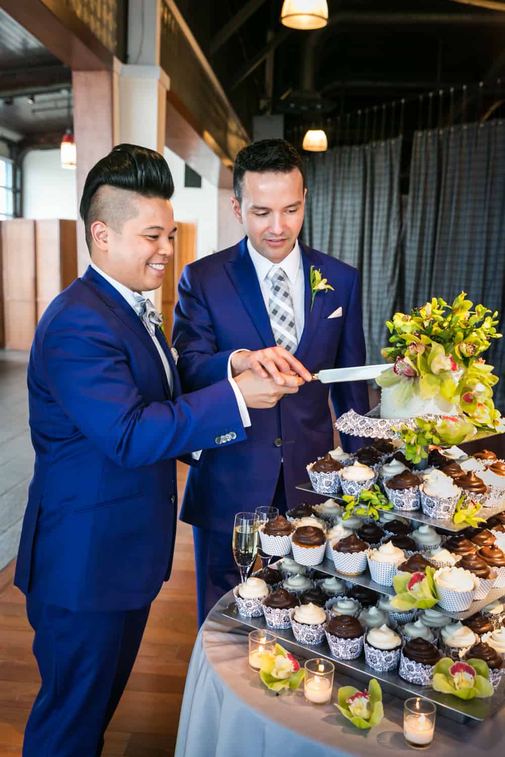 Two grooms cutting cake at a Lighthouse at Chelsea Piers wedding