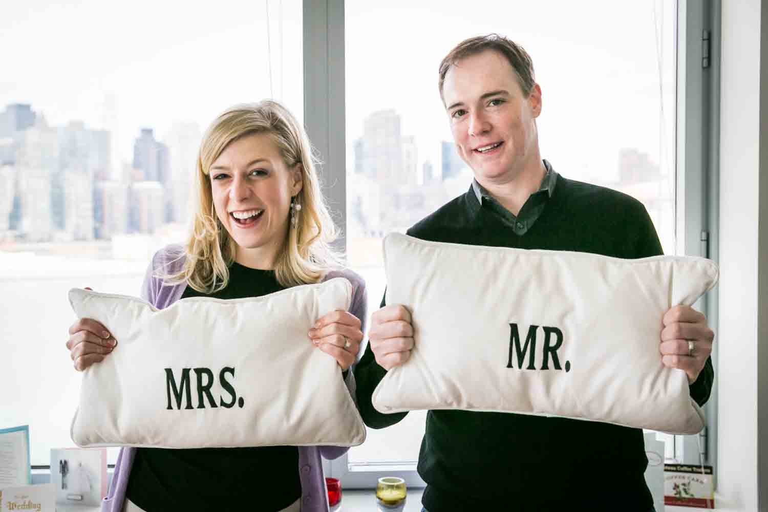 Bride and groom holding Mr. and Mrs. pillows at a Long Island City wedding brunch