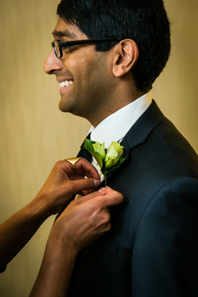 Hands pinning a boutonniere on the groom