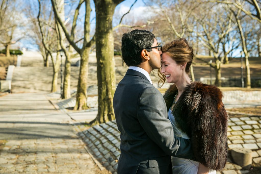 Groom kissing bride on forehead in Fort Greene Park