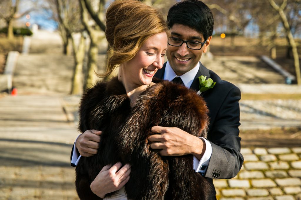 Groom helping bride with faux fur wrap