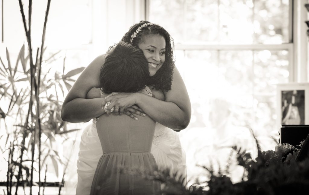 Black and white photo of bride hugging guest