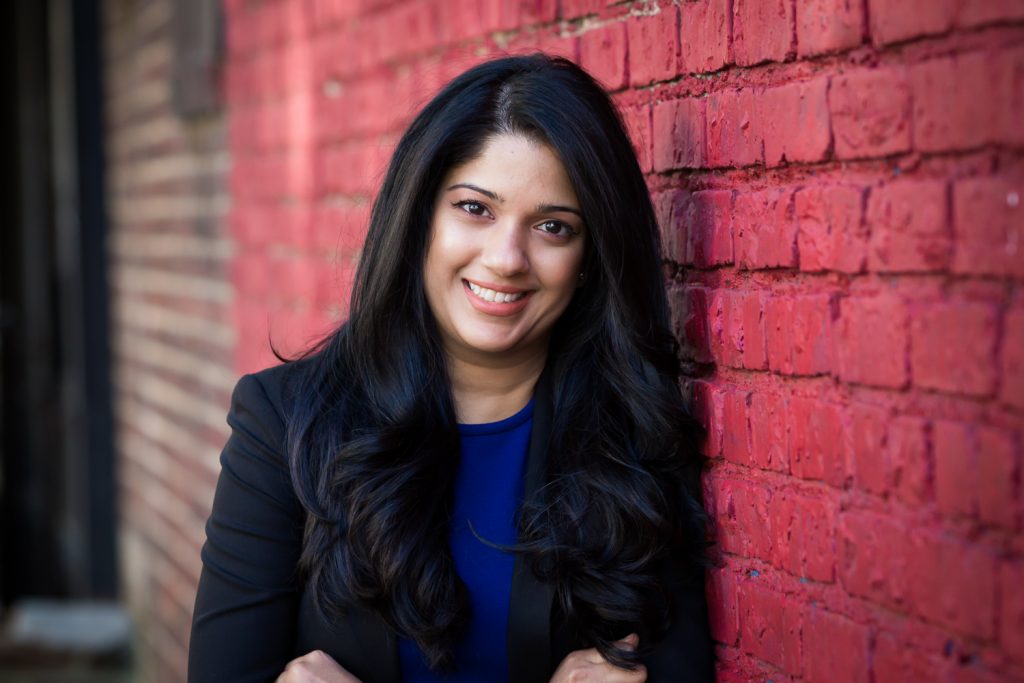 Woman with long dark hair leaning on brick wall for an article on best headshot tips