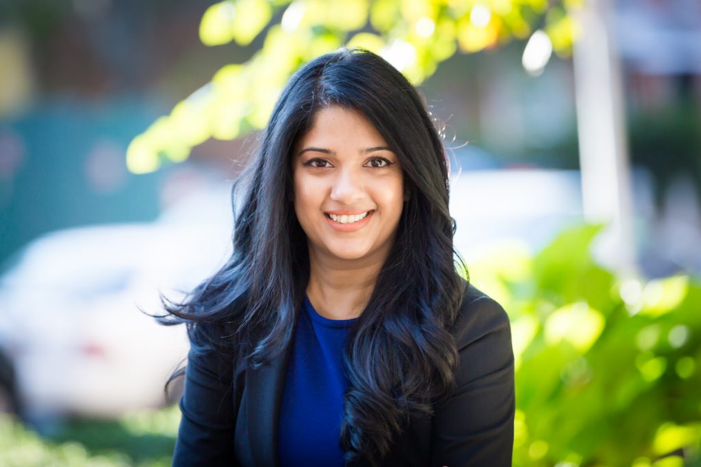 Woman with long dark hair wearing black jacket and blue shirt