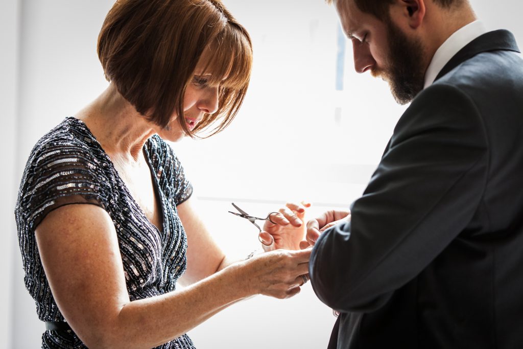 Close up of woman cutting strings off groom's sleeve