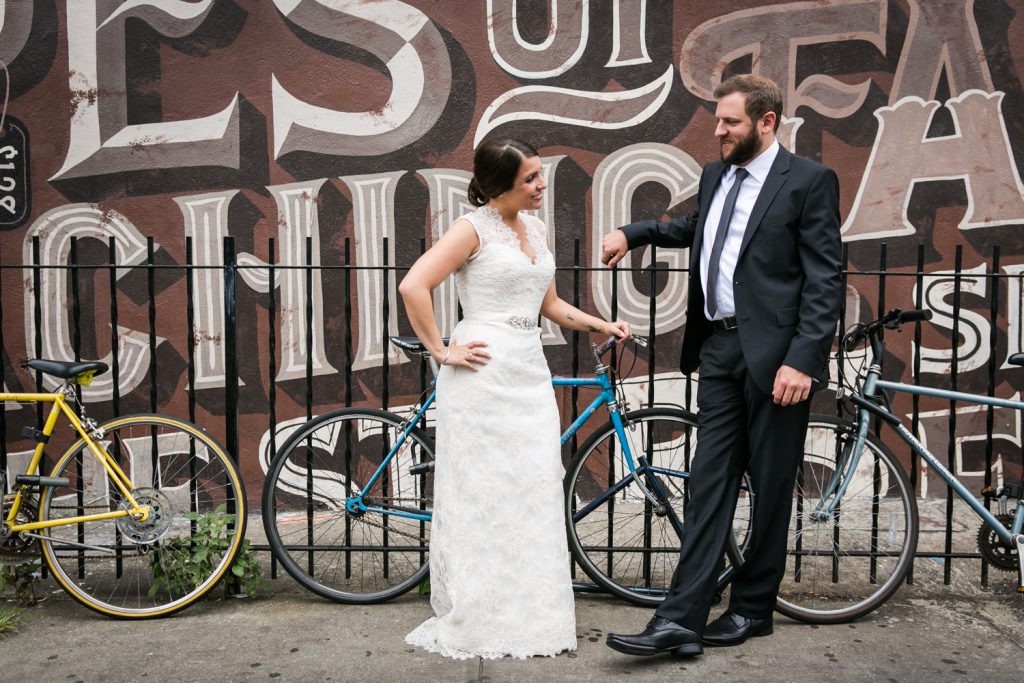 Bride and groom leaning against fence in Williamsburg at a Brooklyn Winery wedding
