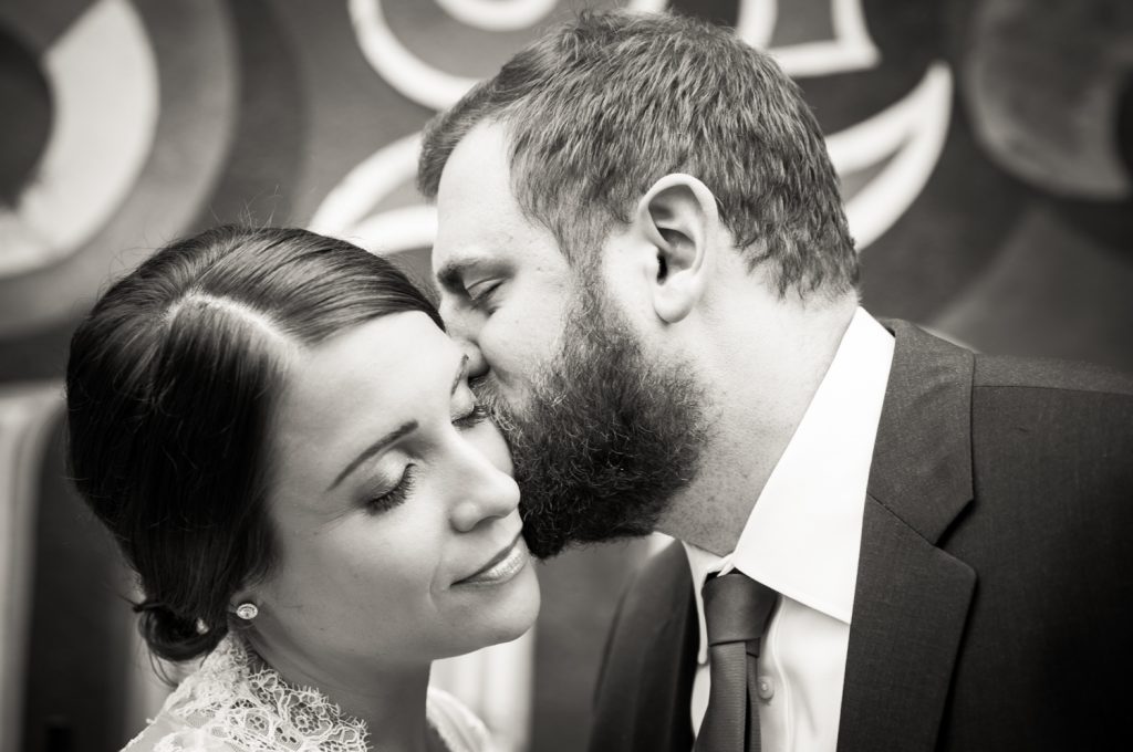 Black and white photo of groom kissing bride's cheek