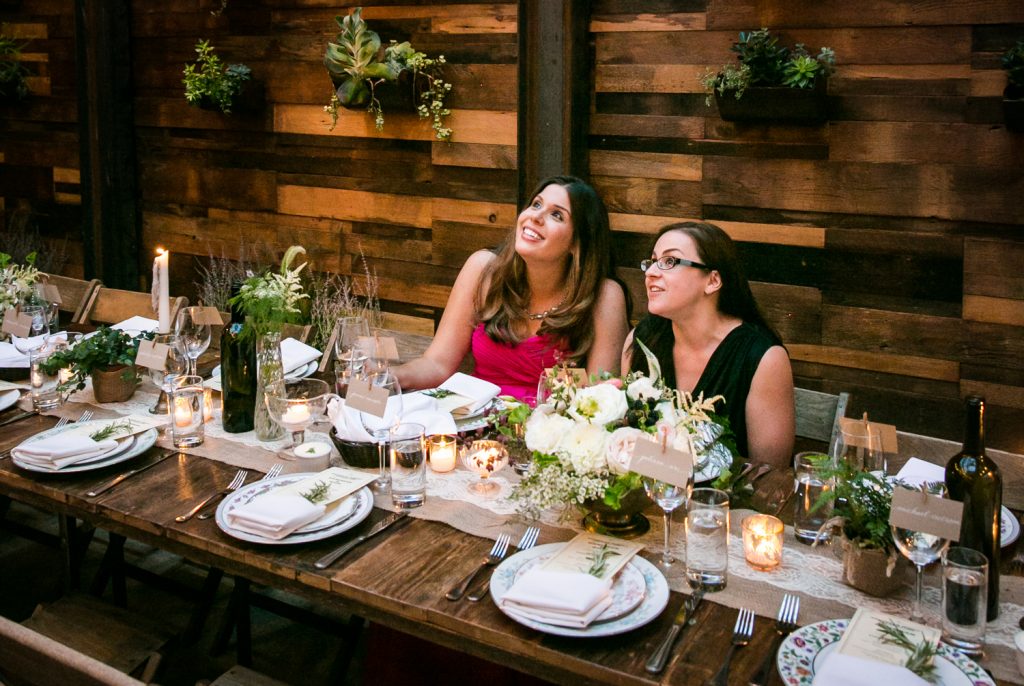 Two guests seated at wooden table at a Brooklyn Winery wedding