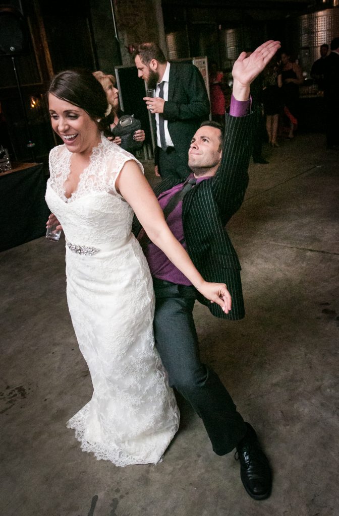 Guest dancing behind bride with hands in the air at a Brooklyn Winery wedding