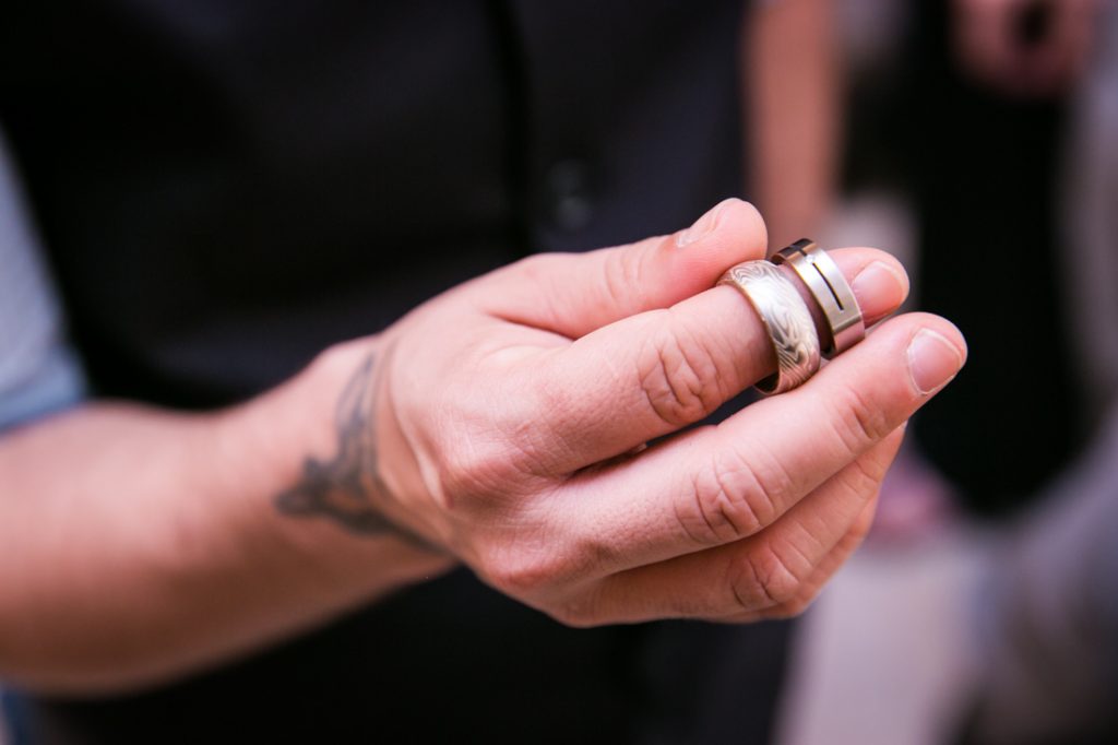 Groom's hand holding two wedding rings before a NYC LGBTQ City Hall wedding
