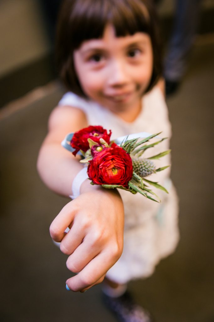 Little girl showing red flower wrist corsage before a NYC LGBTQ City Hall wedding