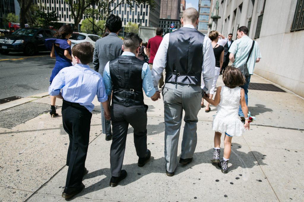 Two grooms walking down sidewalk with children after a NYC LGBTQ City Hall wedding
